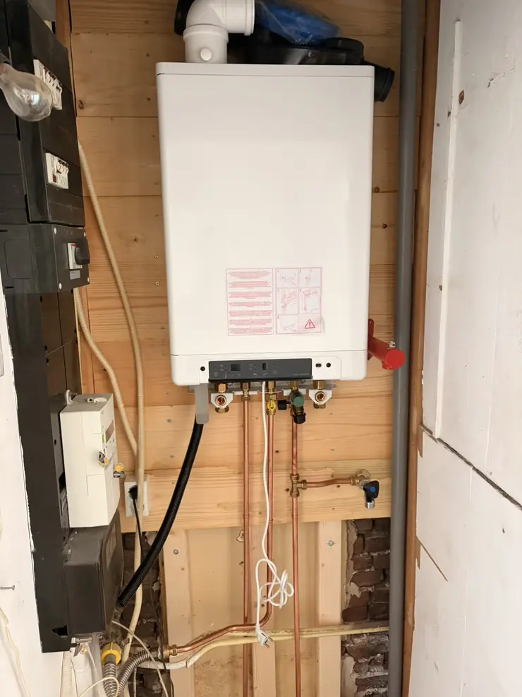 Een nieuwe cv-ketel op een nieuw montagebord in een meterkast